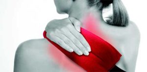 greyscale image where woman is pressing heated pad to upper back