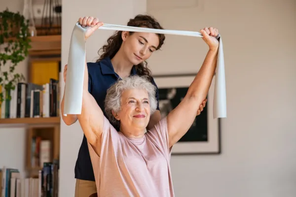 Woman supporting elderly woman with physical therapy using a band