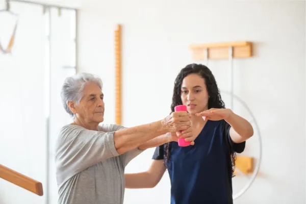 Woman helping elderly woman with physical therapy
