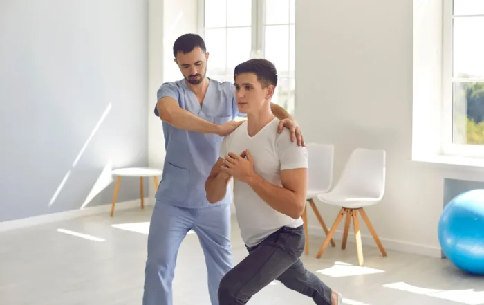 Man assisting younger man in lunges emphasizing physical therapy