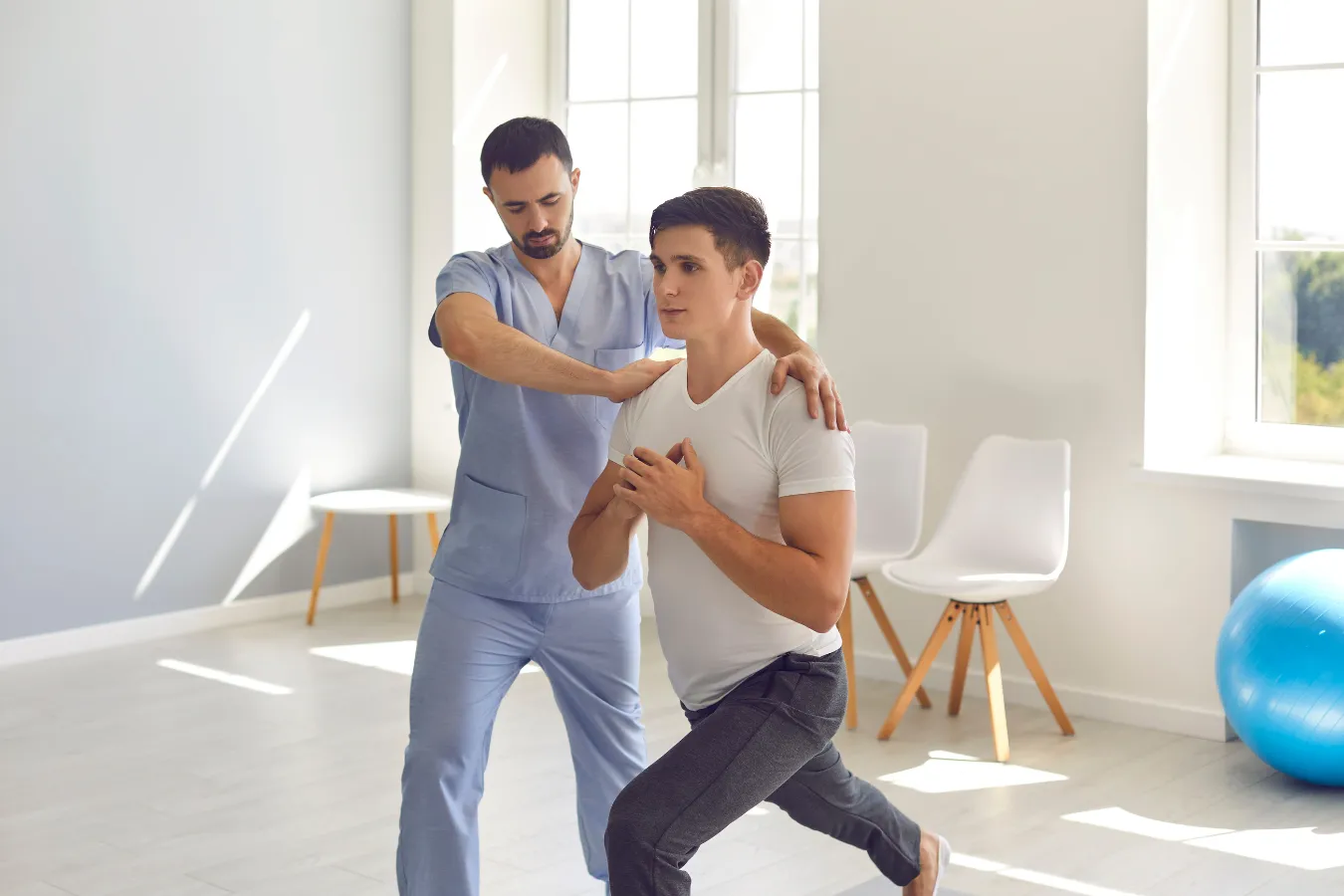 Man assisting younger man in lunges emphasizing physical therapy